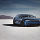 A blue electric sedan sits, baking in the desert sun on a salt flat.
